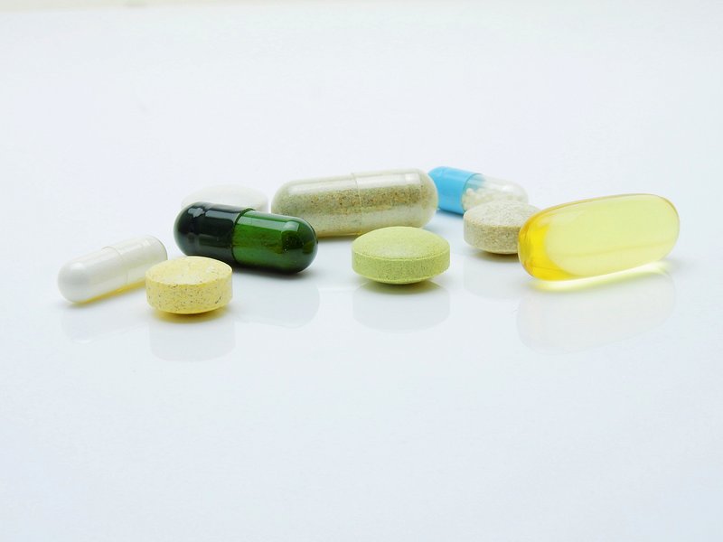 various colorful capsules and tablets on a reflective surface